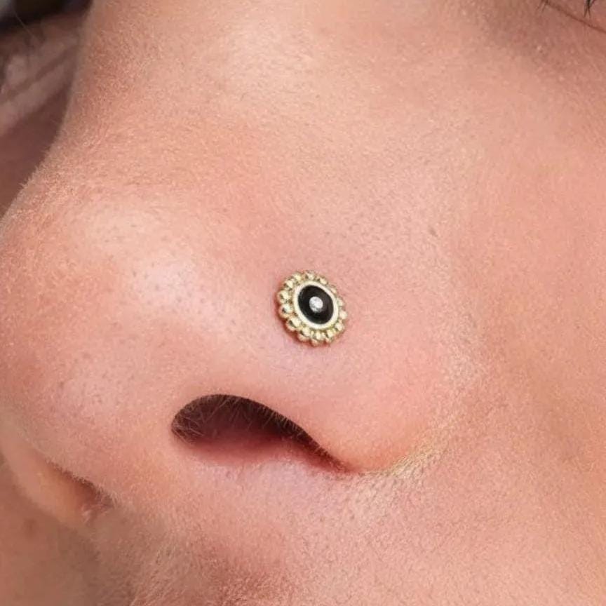 A close-up of a person's nose with a small, ornate nose stud in the center.