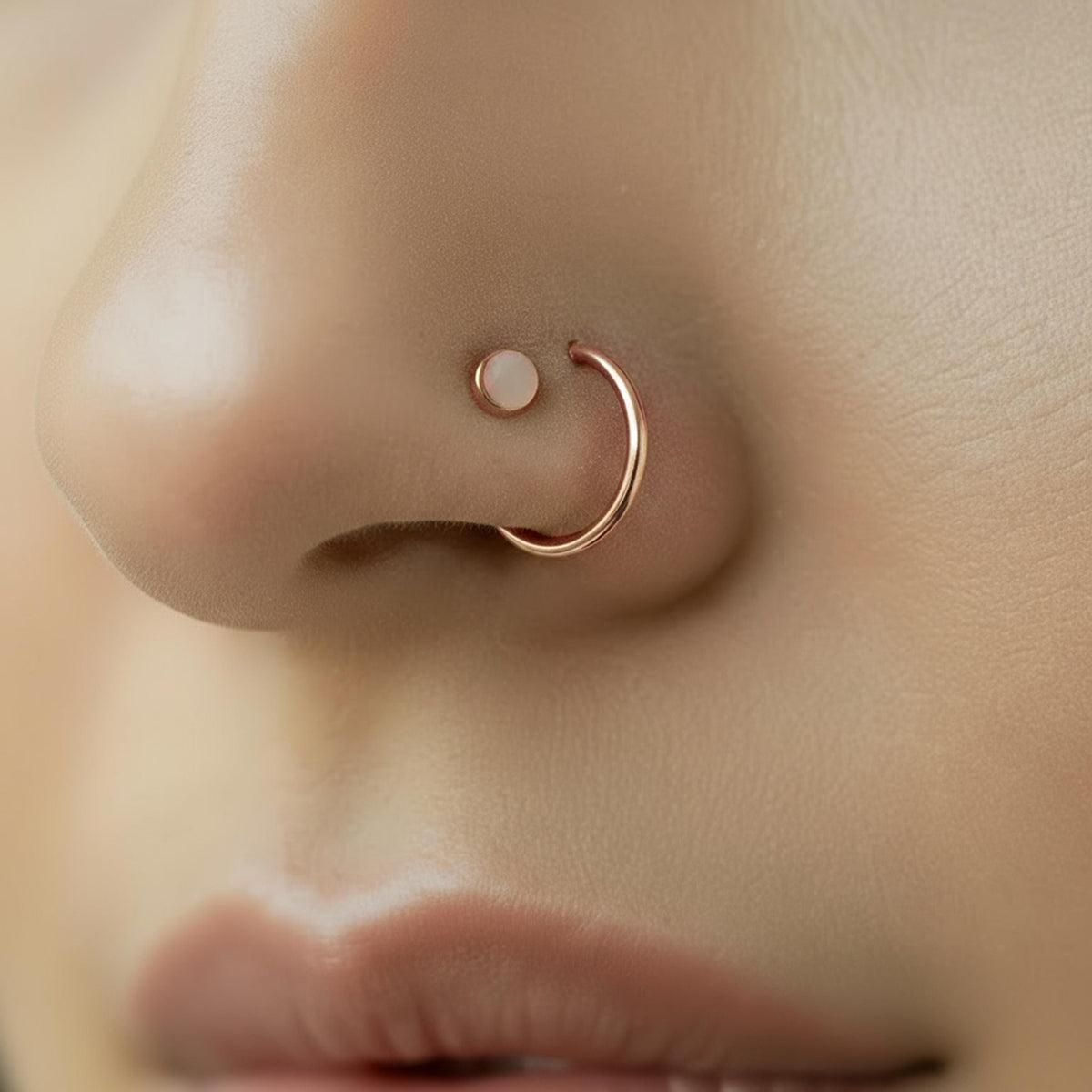 A close-up of a person's nose with a nose ring and a small white stone in the nose ring.
