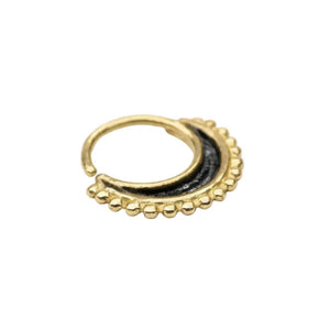 A gold-colored nose ring with a black accent is shown against a white background.