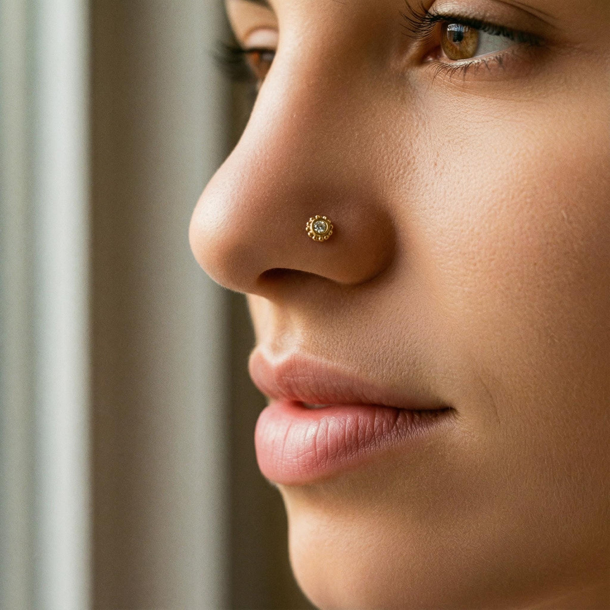 A gold nose ring with a diamond, set in the center.