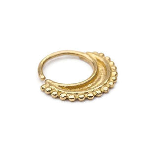 A gold-colored metal earring with a decorative design, featuring a curved shape and small, round beads or stones along the edge.