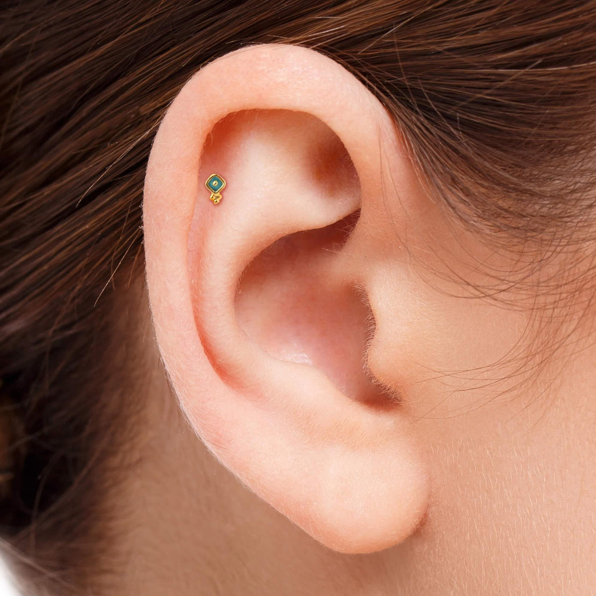 A close-up view of a person's ear, showing a small earring or stud in the earlobe.