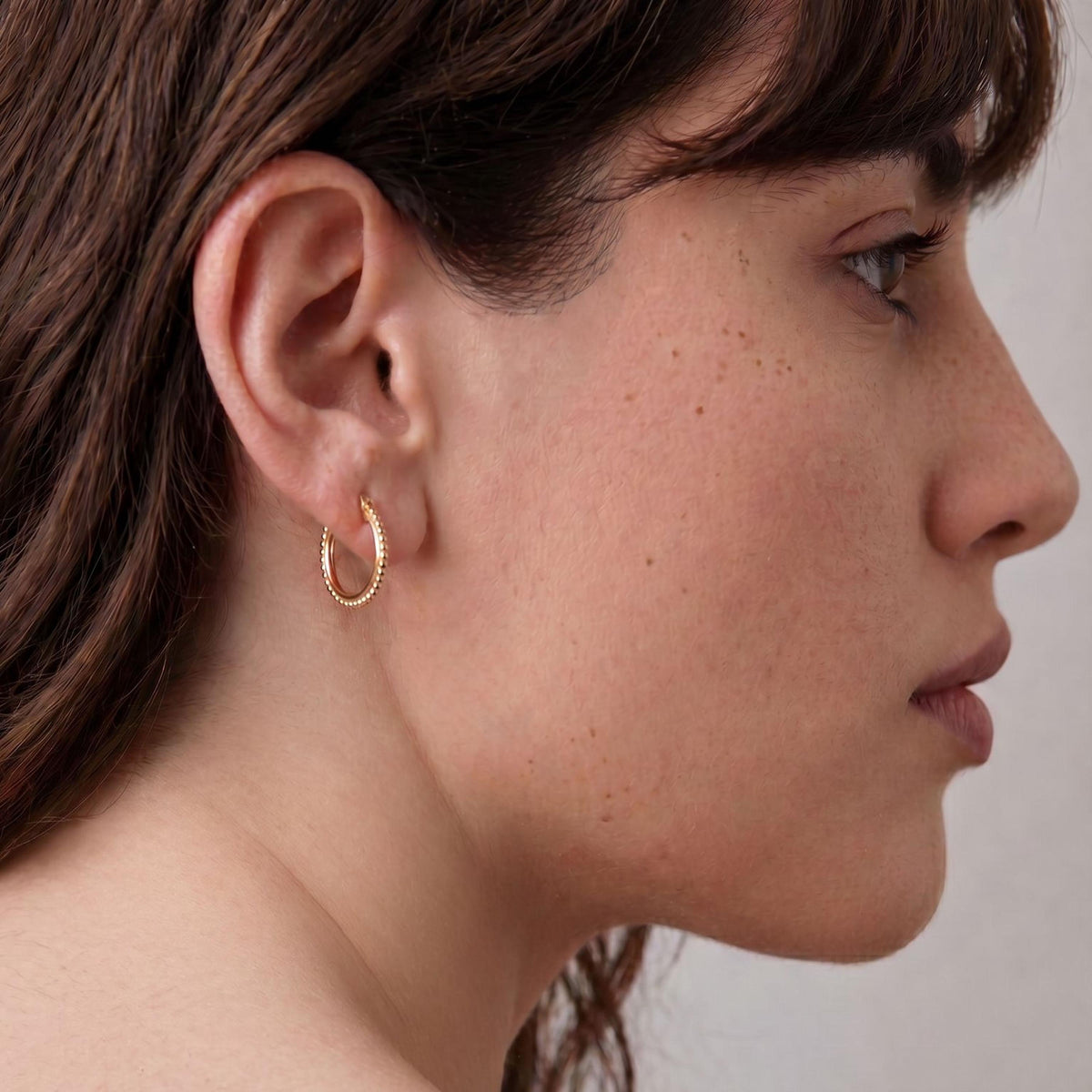 A close-up of a woman's face, focusing on her ear and cheek area.