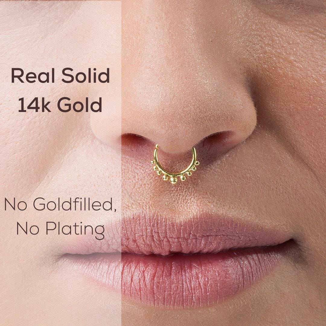 Tribal Indian Septum Ring: The image is a close-up of a person's nose and mouth, featuring a gold nose ring.