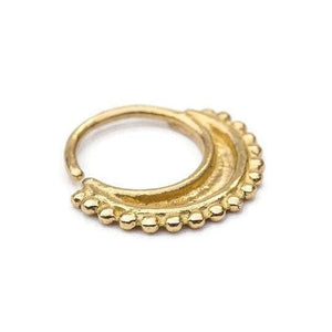 A gold-colored metal nose ring with a decorative design.