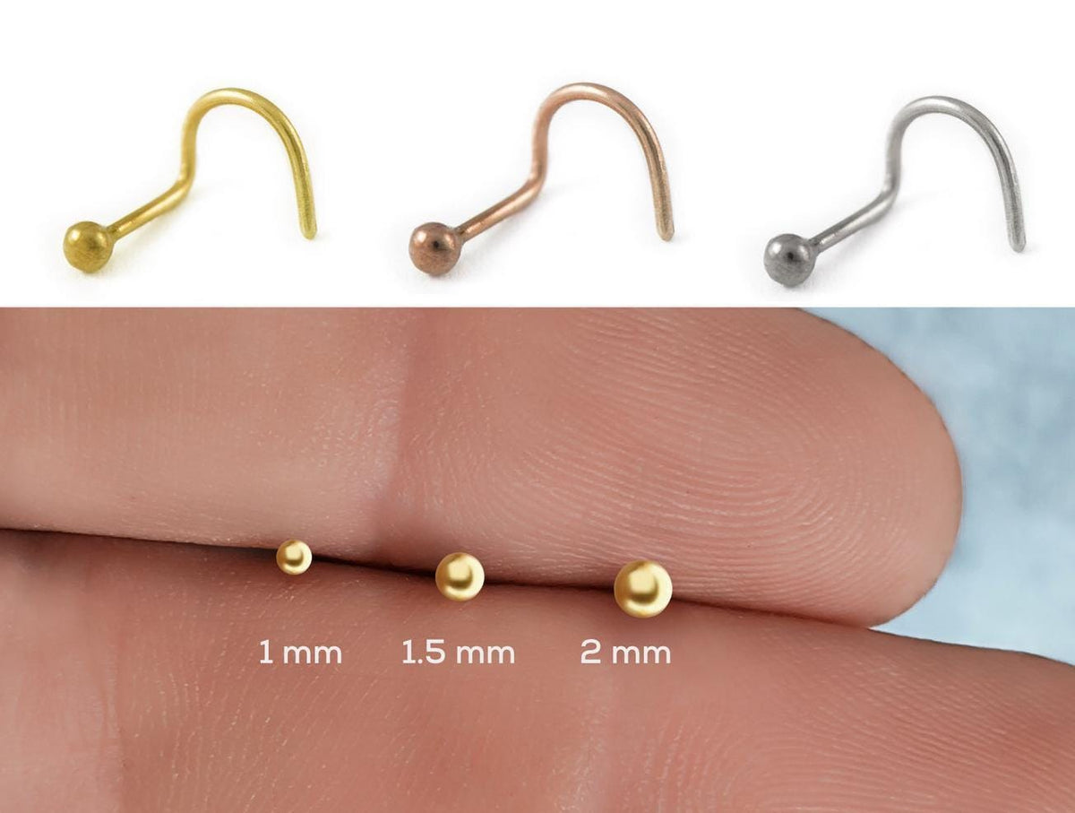 four different sizes of nose studs, ranging from 1 mm to 2 mm in diameter, arranged in a descending order.