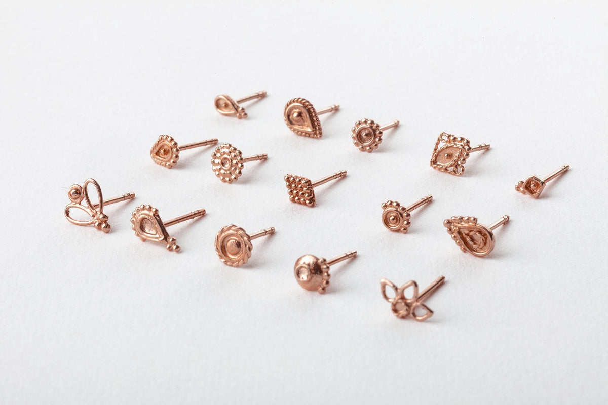 a collection of variously shaped and designed earrings made of copper, arranged on a white background.