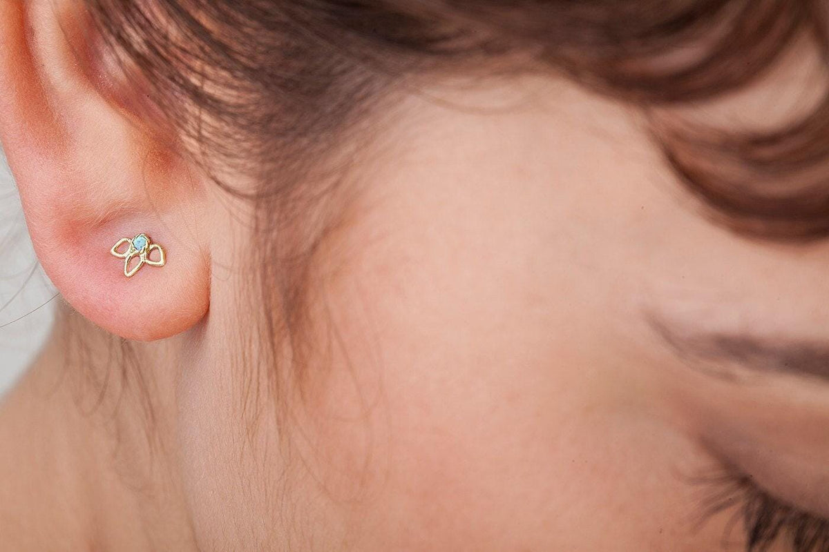 A close-up view of a person's ear with a small gold earring in the earlobe.
