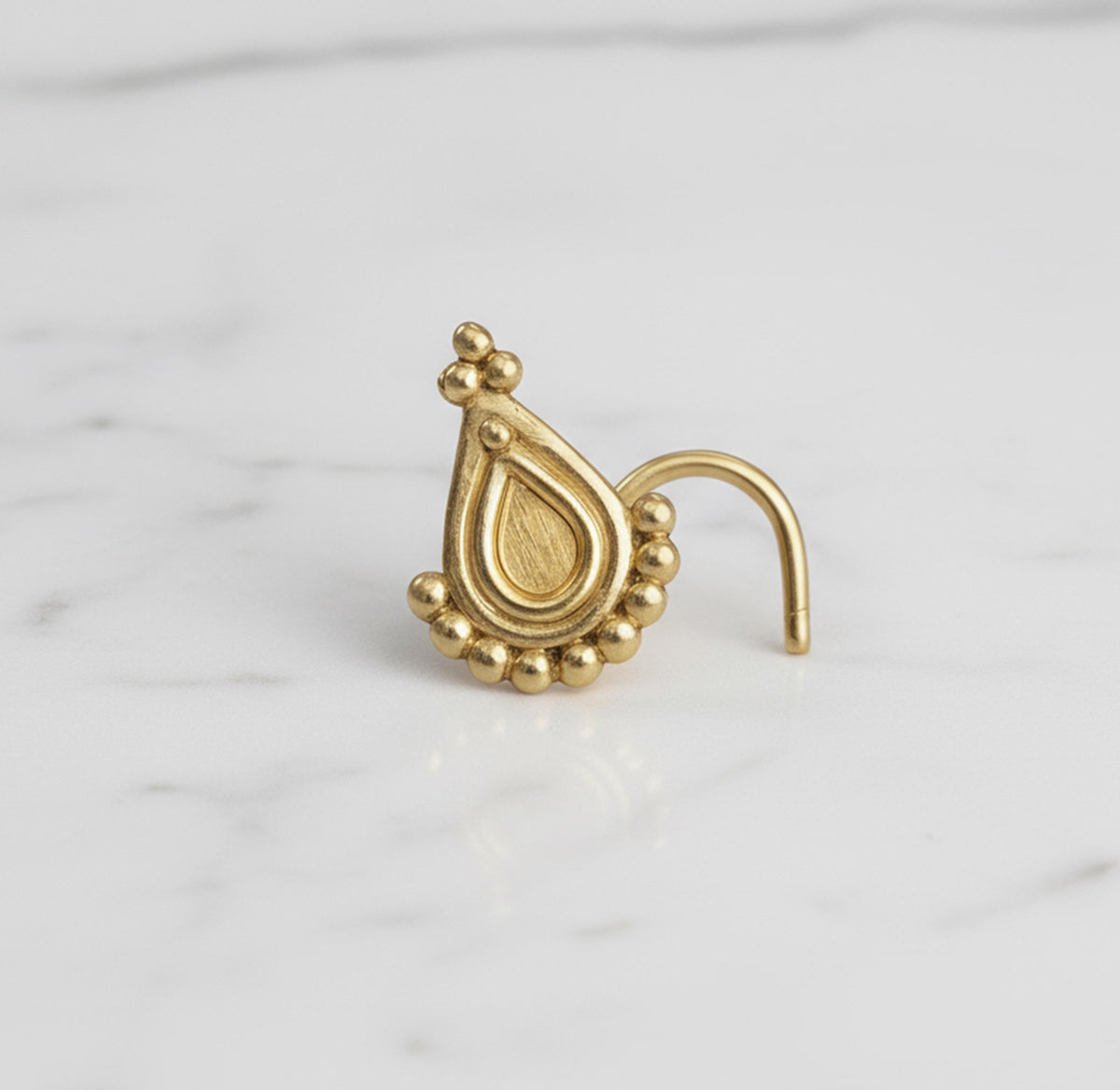 Nose Stud Jewelry: A gold-colored nose stud with a decorative pendant is shown against a white marble background.