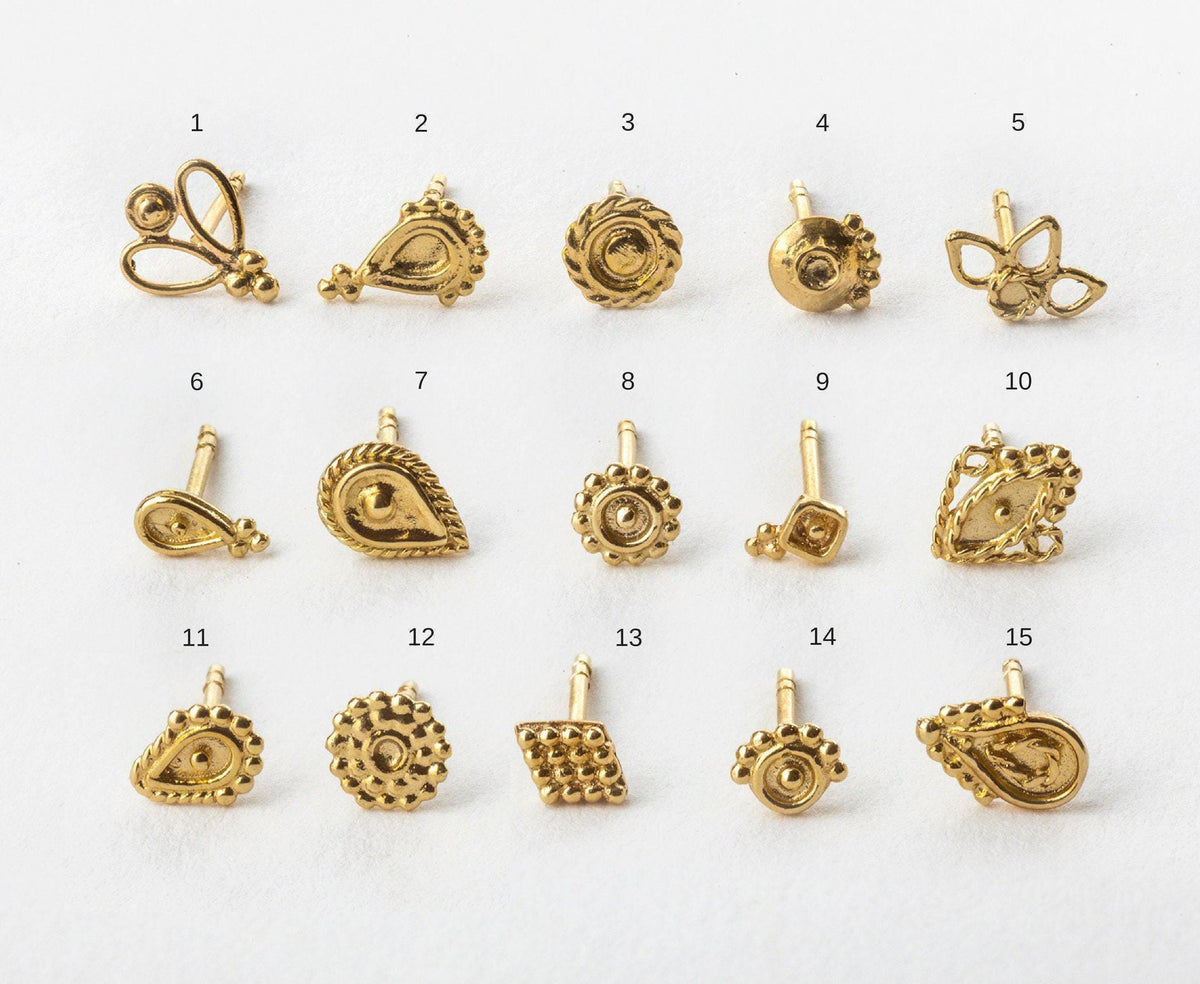 a collection of various gold-colored earrings or earring backs, each with unique designs and shapes.