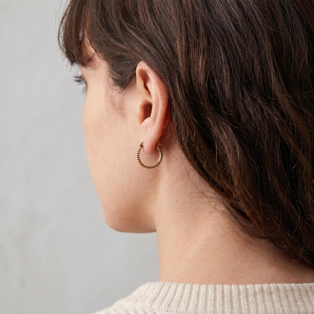 A close-up view of a woman's face, focusing on her ear and the side of her head.