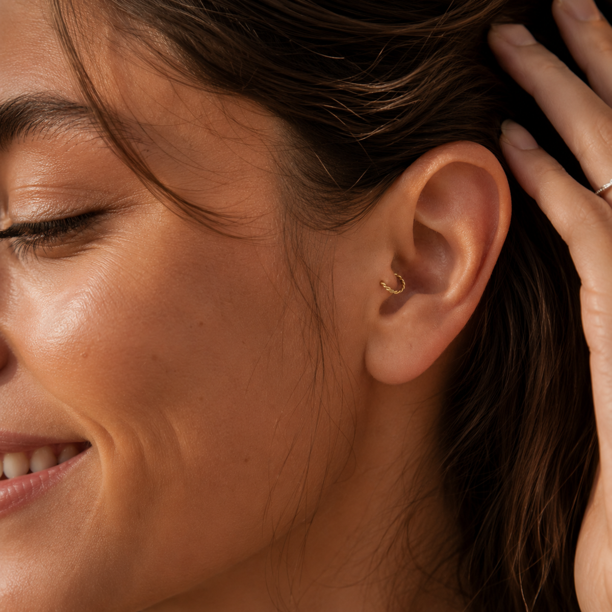 A close-up of a woman's face, focusing on her earrings and smiling expression.