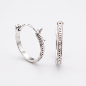 A pair of silver earrings with a cross-shaped clasp and a textured band design.