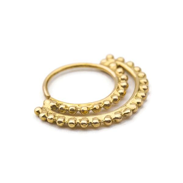 A gold-colored metal ring with a decorative design of small, round beads or stones.