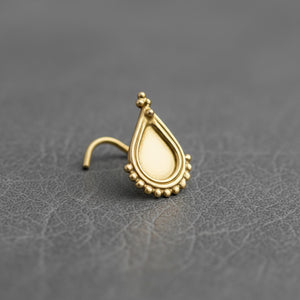 A gold-colored earring with a teardrop-shaped design and small decorative elements is displayed on a gray surface.