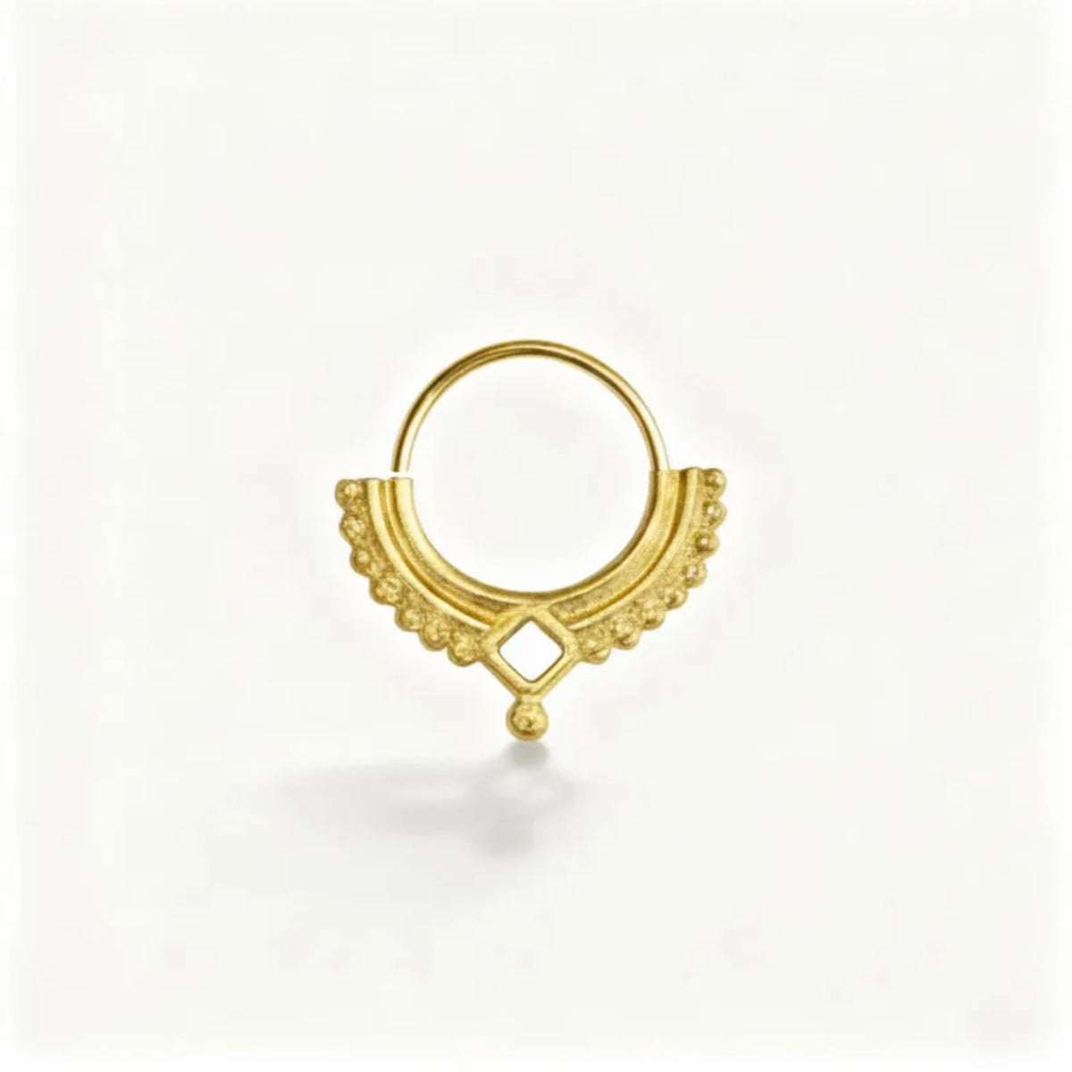 A gold-colored metal ring with a decorative design, featuring a small gemstone or bead at the center.