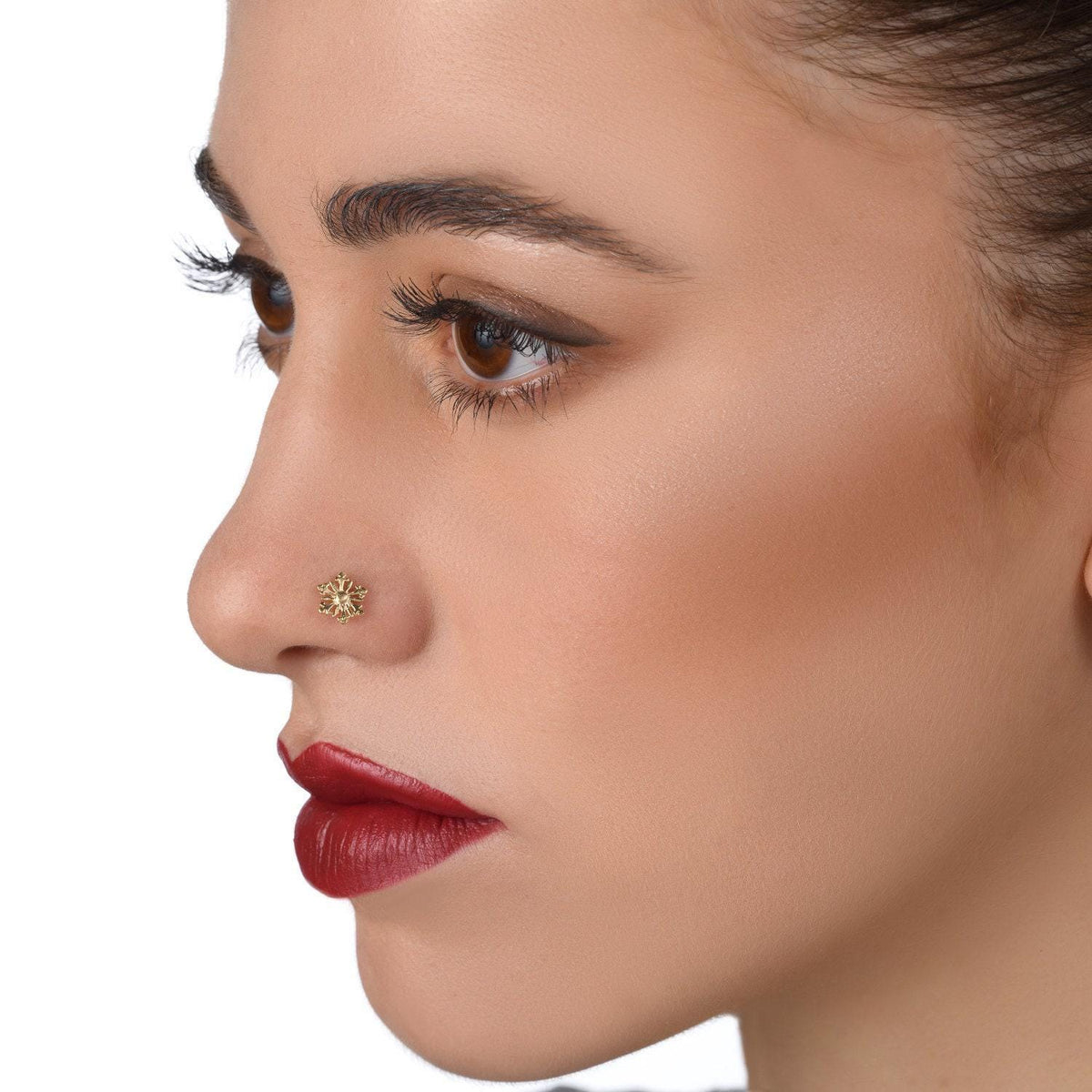 A close-up of a woman's face, focusing on her nose and lips. She has dark hair and is wearing a gold nose stud.