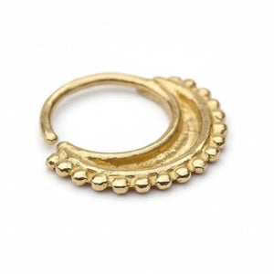 A gold-colored metal nose ring with a decorative design.