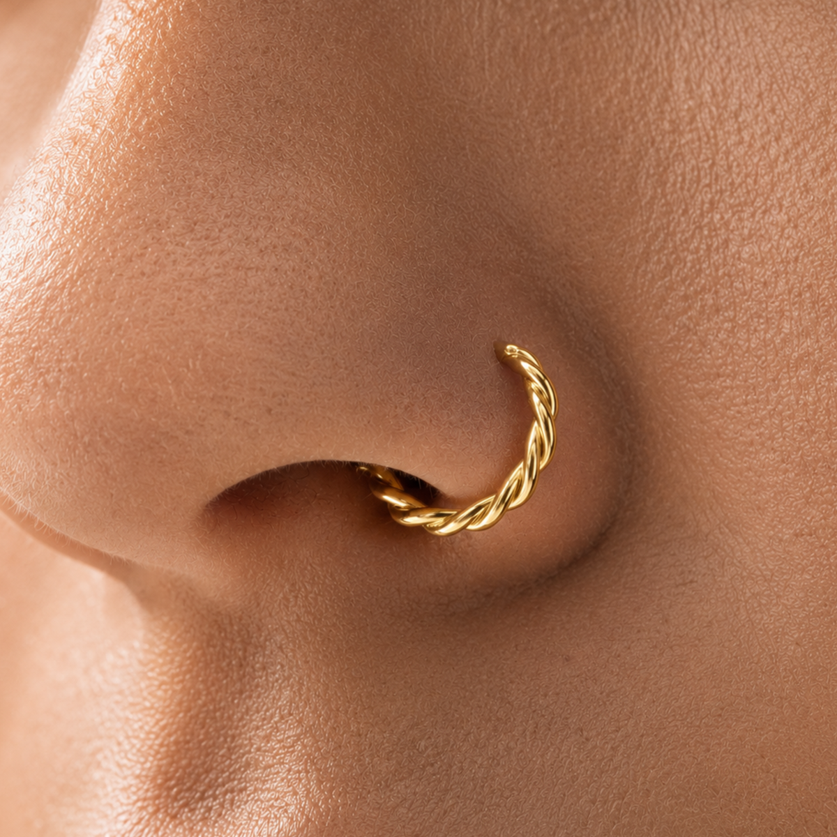 A close-up of a person's nose with a gold-colored nose ring.