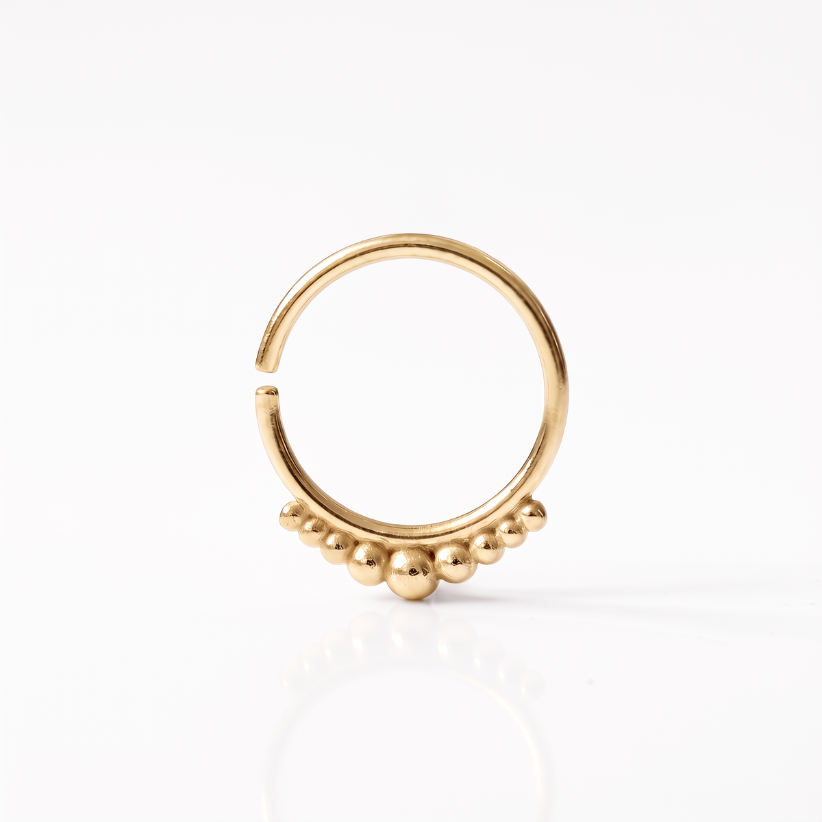 A gold-colored ring with a decorative element of small balls or stones on the surface.
