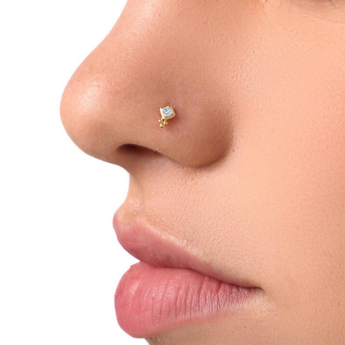 A close-up of a person's nose with a small gold-colored nose stud.
