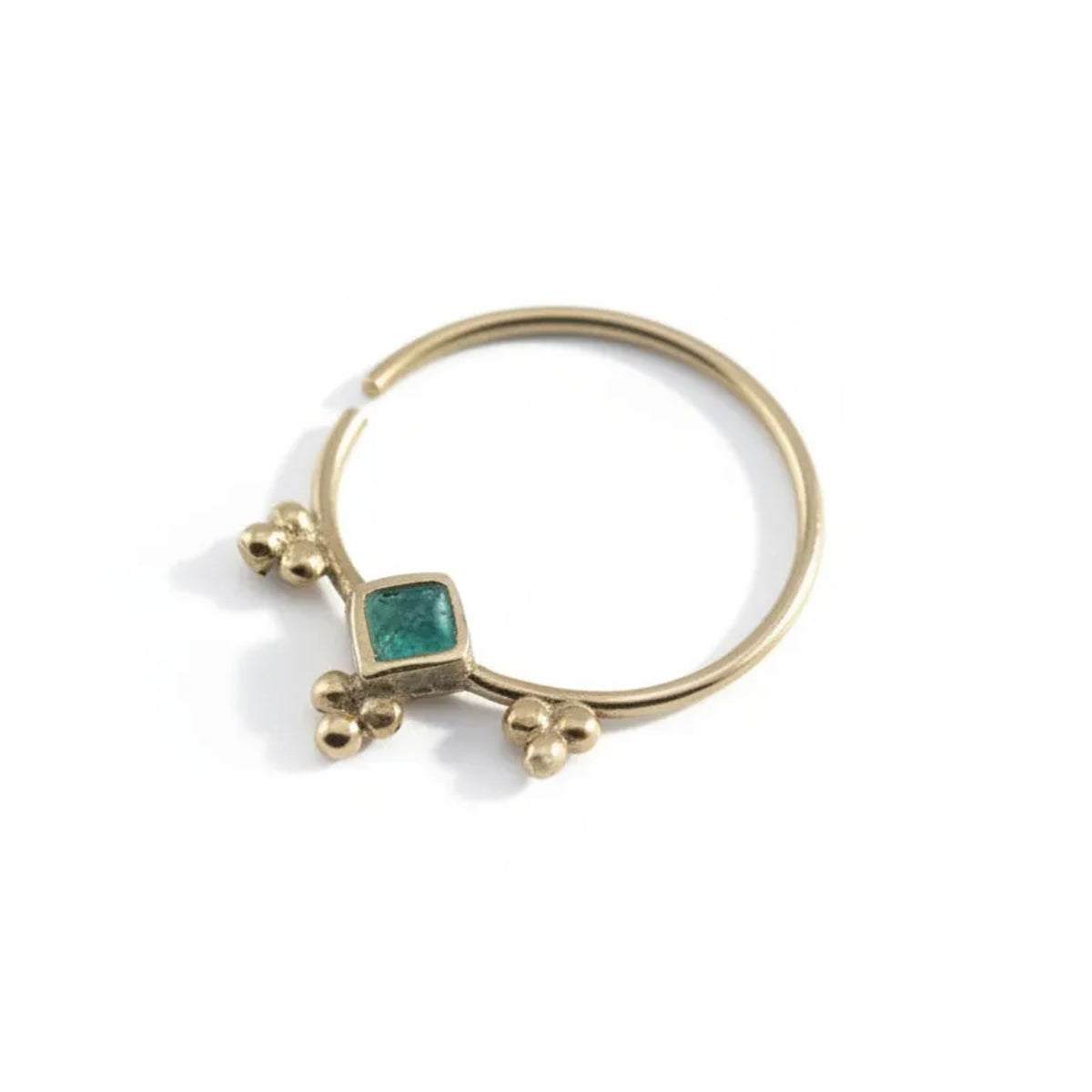 Dainty Gold Nose Ring: A gold-colored nose ring with a green gemstone in the center.