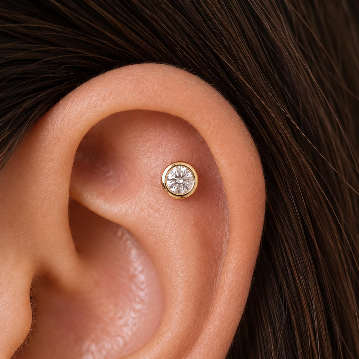 A close-up of a person's ear with a diamond-encrusted earring in the earlobe.