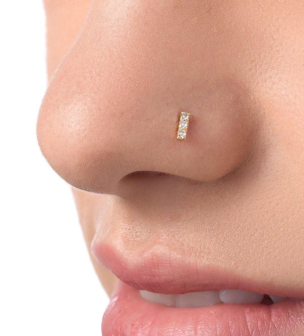 A close-up of a person's nose with a small gold-colored nose stud or piercing.