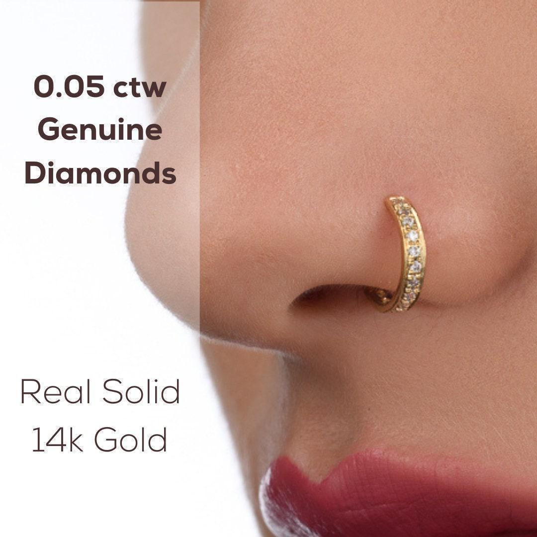 Diamond Nose Ring: a close-up of a person's nose and lips wearing a gold nose ring with a diamond accent.