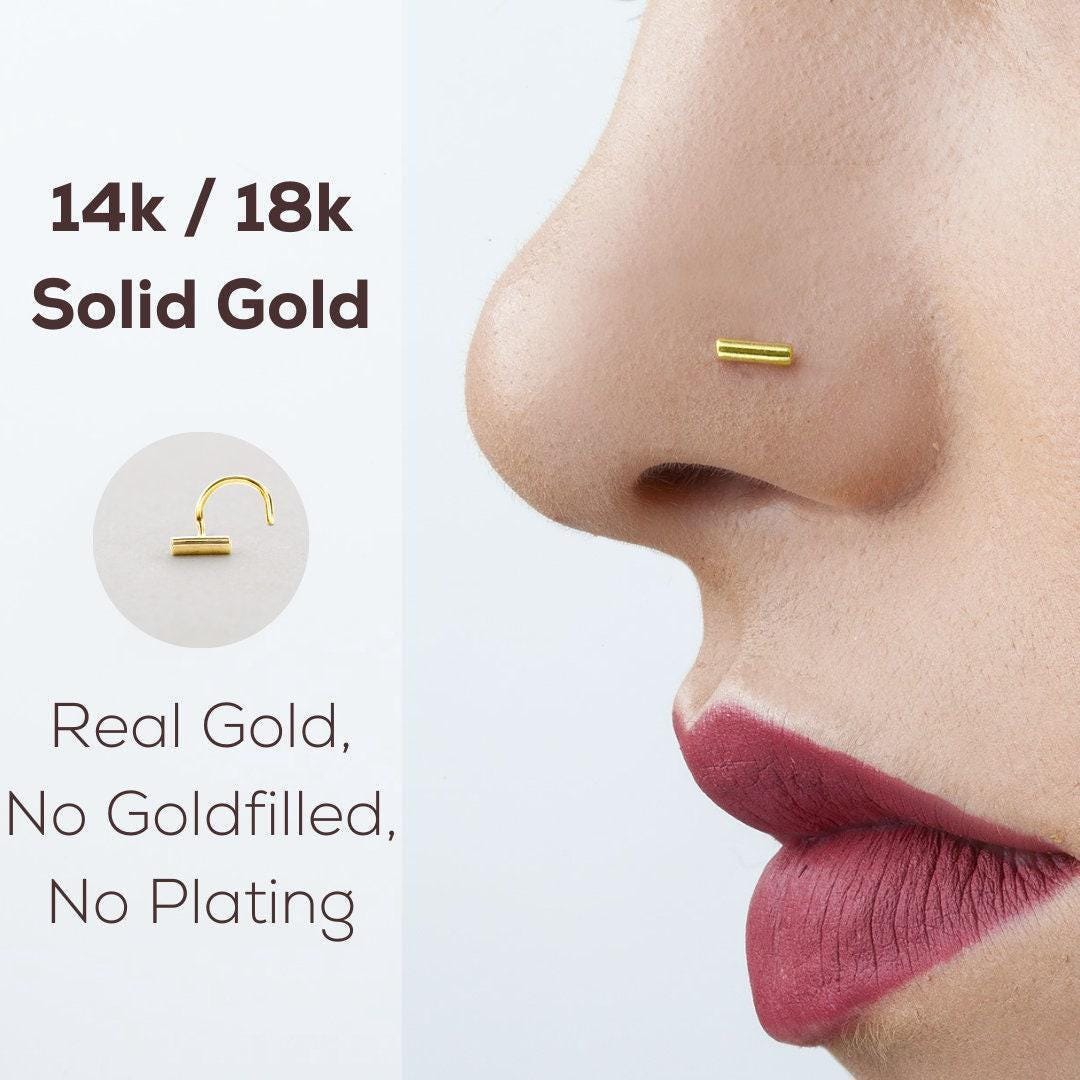 a close-up of a person's nose with a gold-colored nose ring.