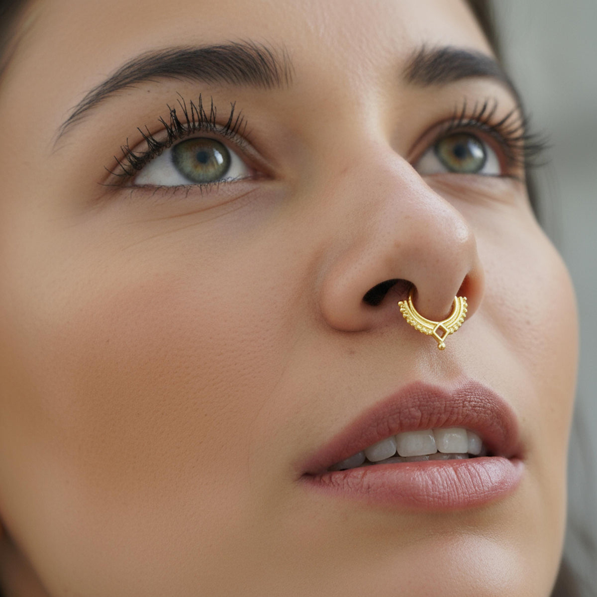 A close-up of a woman's face, focusing on her nose and lips, with a gold nose ring visible.