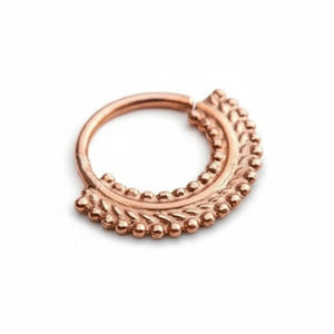 A copper-colored metal ring with a decorative leaf-like design on the surface.