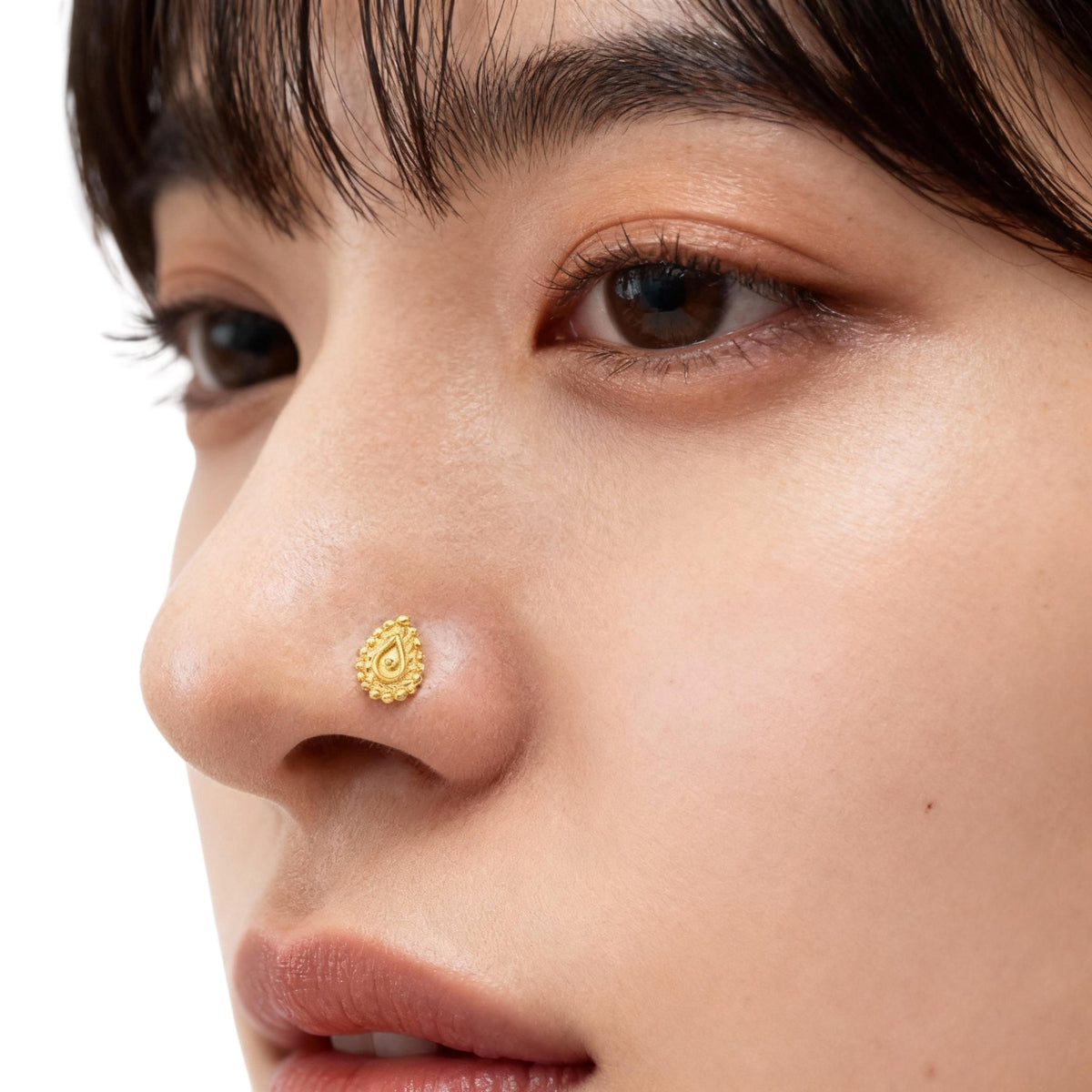 A close-up of a person's face, focusing on their nose and the gold nose ring.