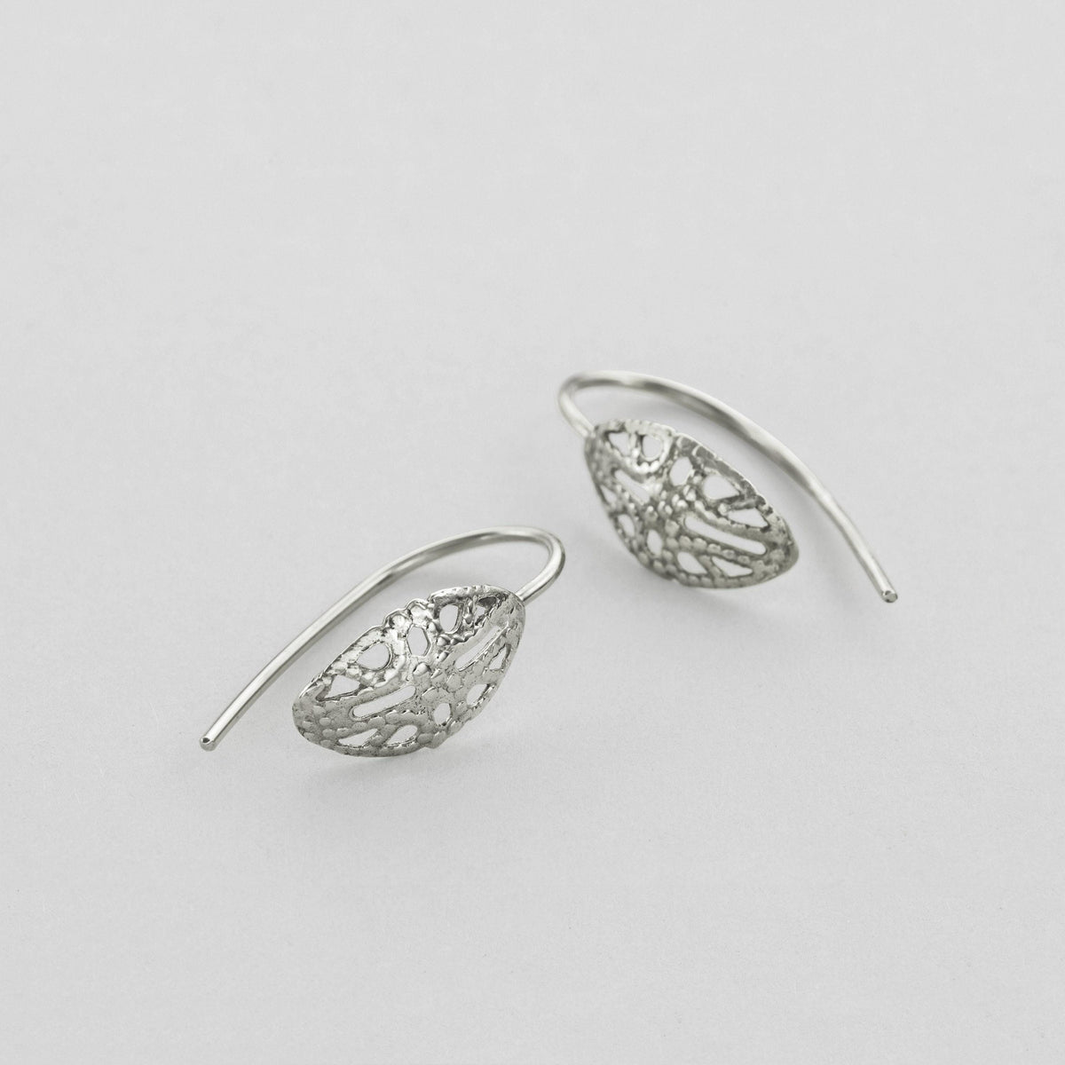 A pair of silver earrings with intricate leaf-like designs.