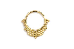 A gold-colored metal ring with a decorative design featuring small balls or beads around the edges.