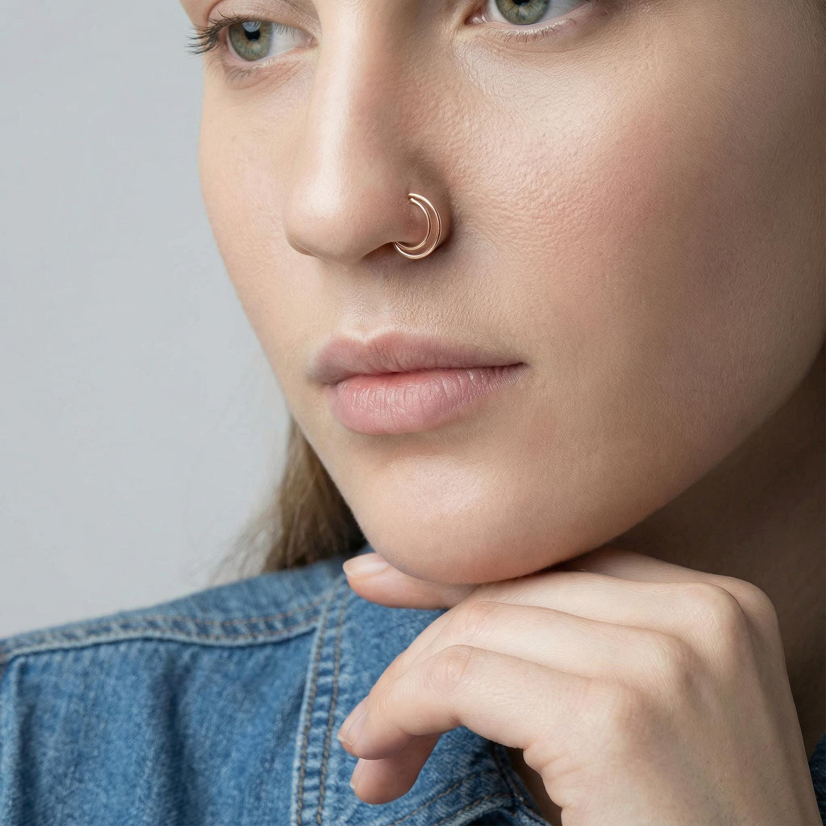 A close-up of a woman's face, focusing on her nose and chin, with a thoughtful expression.