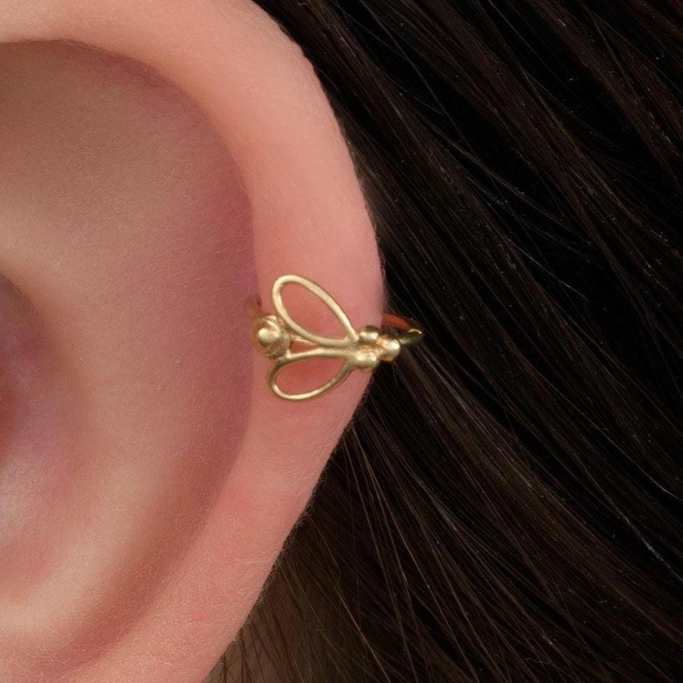 Butterfly Helix Hoop Earring: A close-up of a person's ear adorned with multiple gold earrings, including hoop earrings and a piercing.