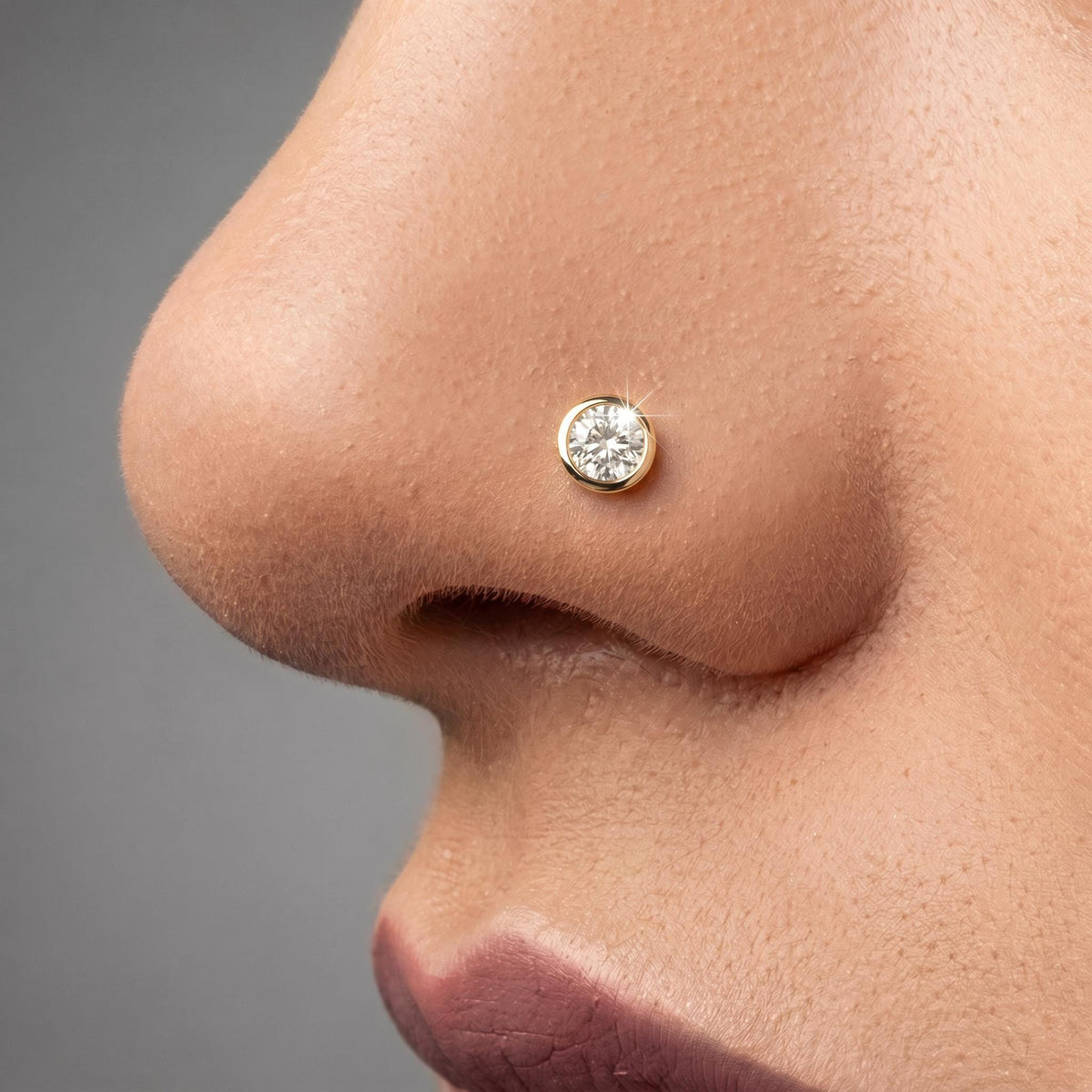 A close-up of a person's nose with a small, round diamond-encrusted nose ring.