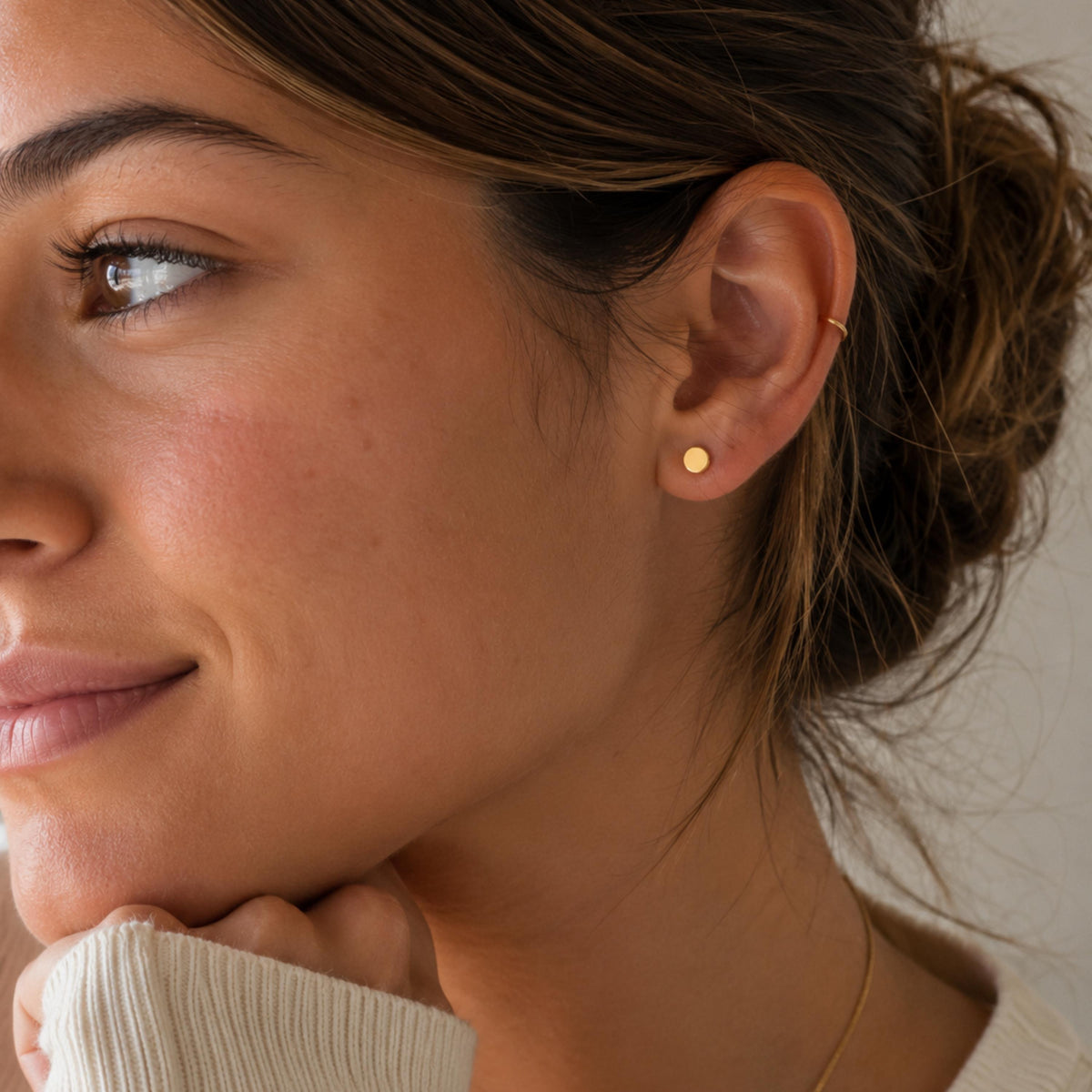 A close-up of a woman's face, focusing on her earrings and the side of her face.