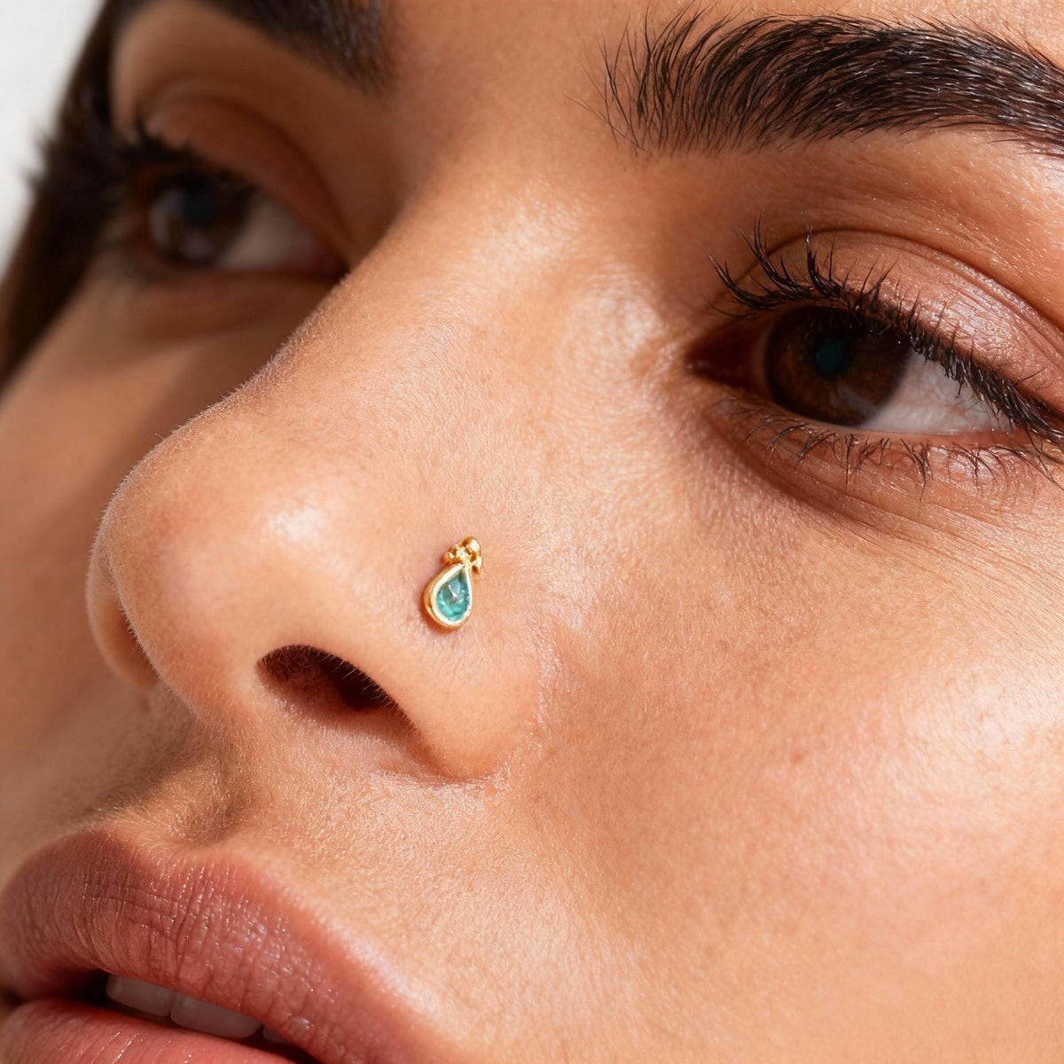 A close-up of a person's face, focusing on their nose and the small, ornate nose ring.