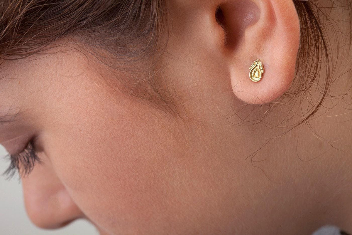 A close-up of a person's face, focusing on their ear with a small gold earring.