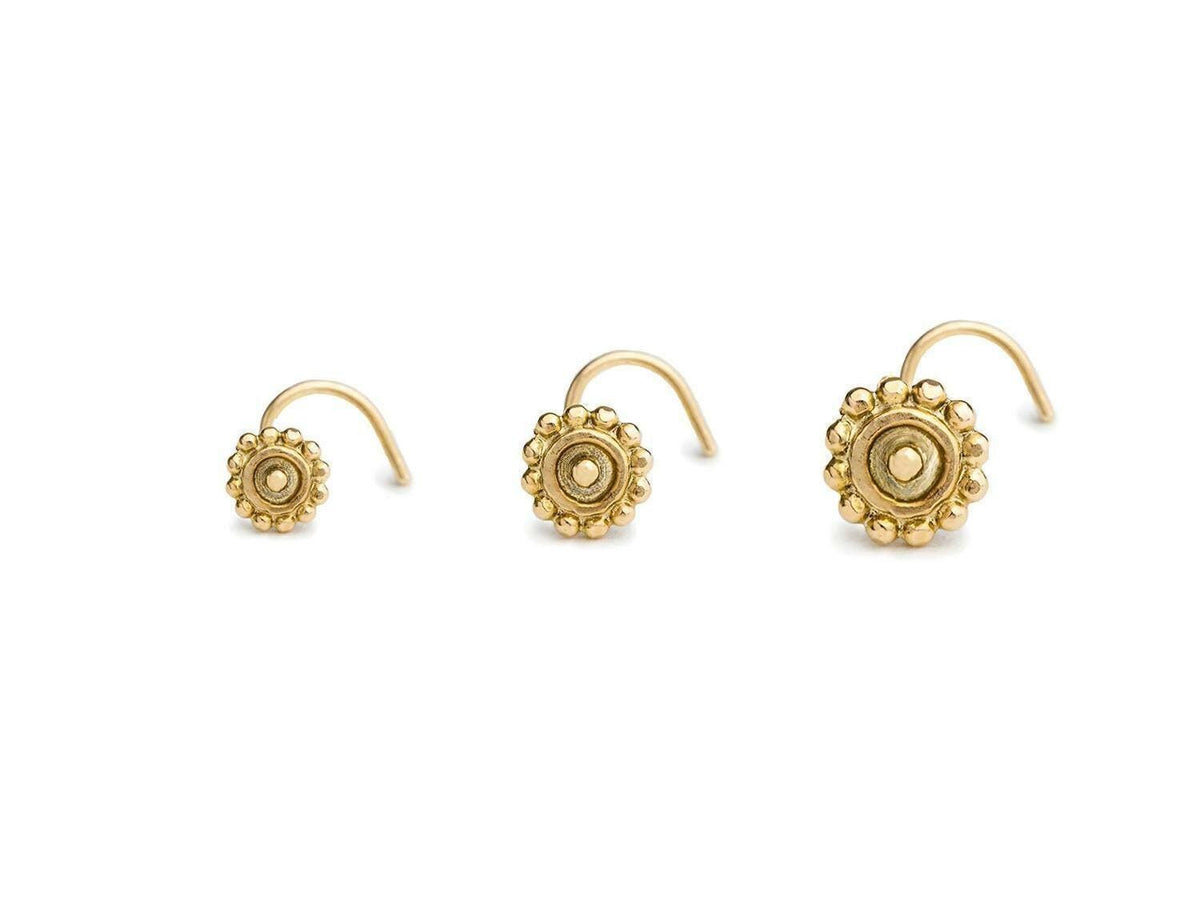 Three gold-colored nose studs with intricate floral designs.