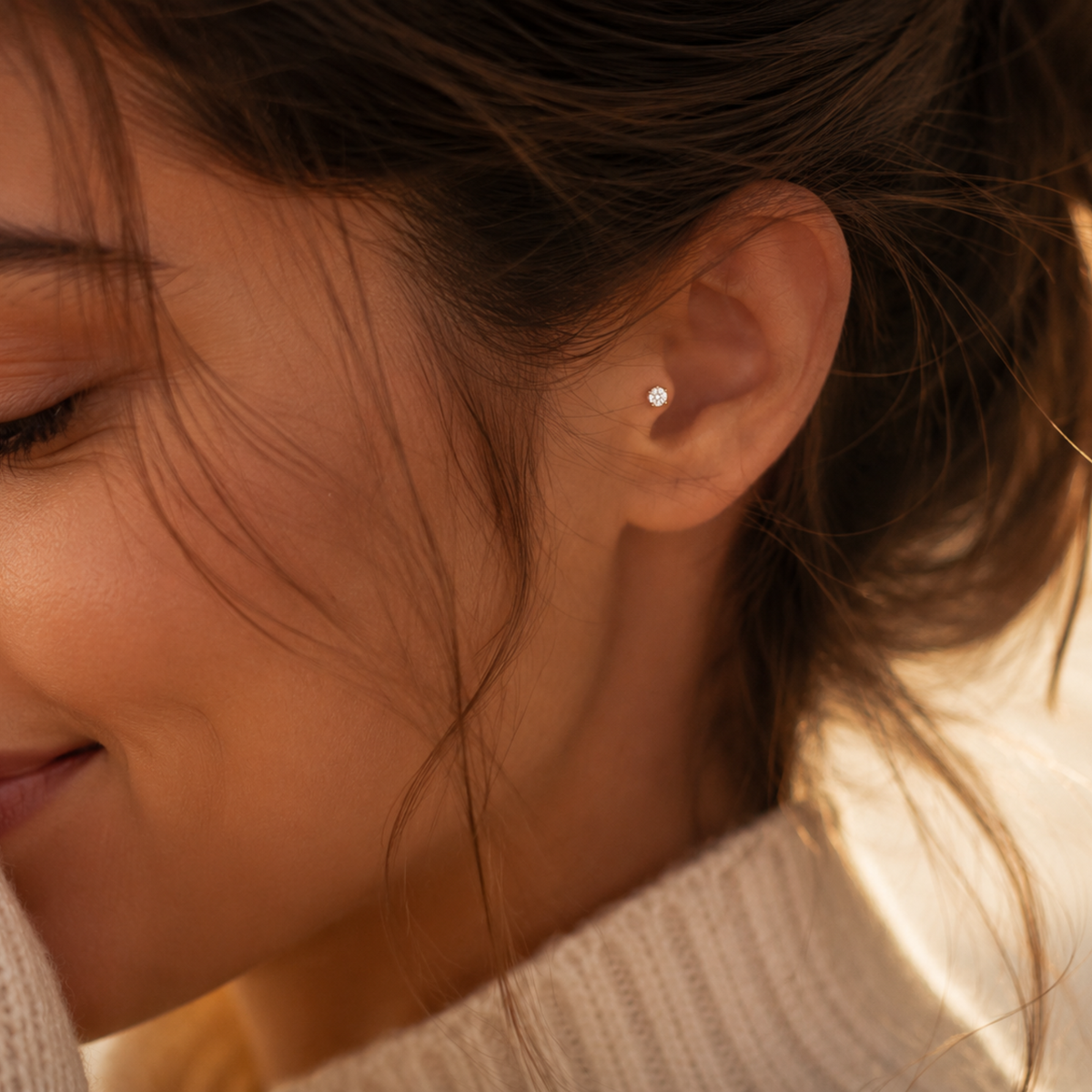 A close-up of a woman's face, focusing on her ear with a small diamond earring.