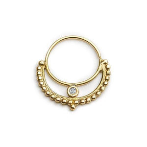 A gold-colored earring with a diamond at the center, featuring a decorative design with small beads around the outer edge.