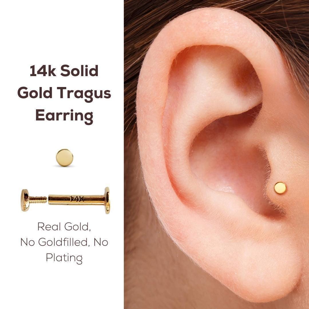 Tiny Solid Gold Tragus Earring: a close-up of a person's ear with a 14k gold piercing earring inserted into it.