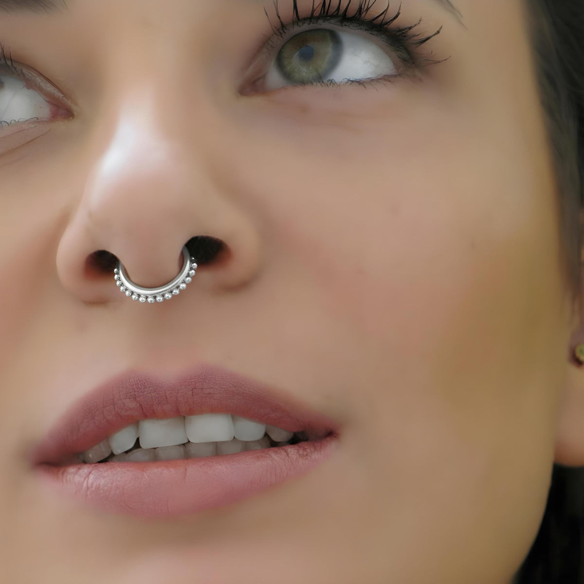A close-up of a woman's face, focusing on her nose and lips, with a nose ring visible.