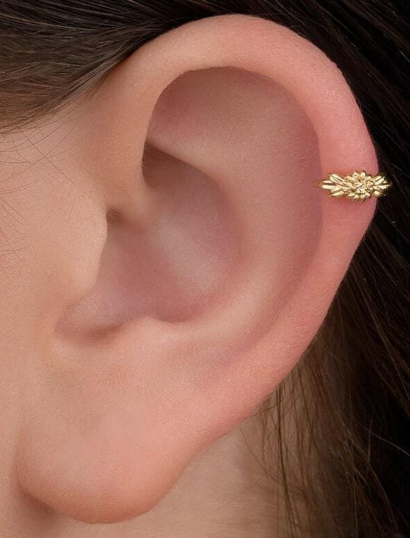 Flower Cartilage Hoop: A gold earring with a floral design is visible in the image.