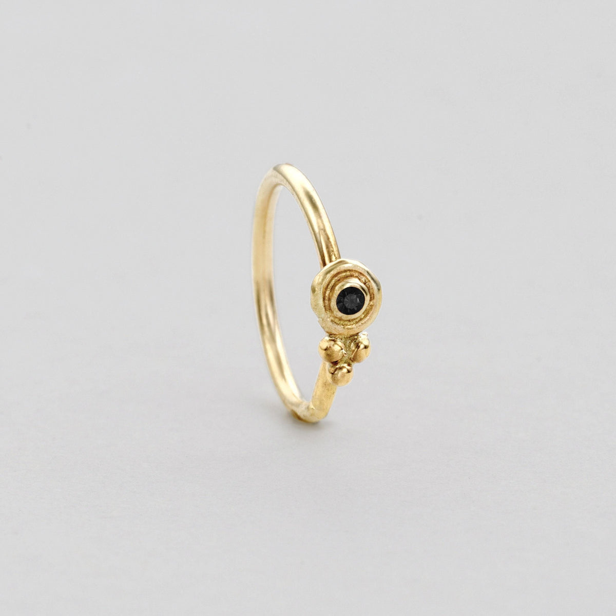 A gold ring with a black gemstone, possibly a diamond, set in the center.