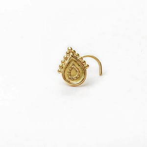 A gold-colored nose stud with an intricate design on the front.