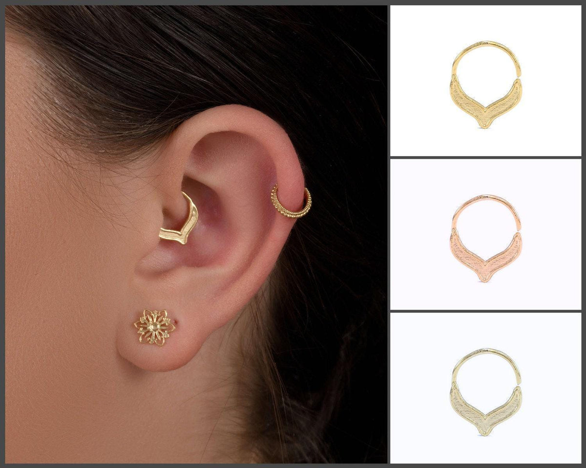 a close-up of a person's ear with a gold earring and a gold ring piercing.